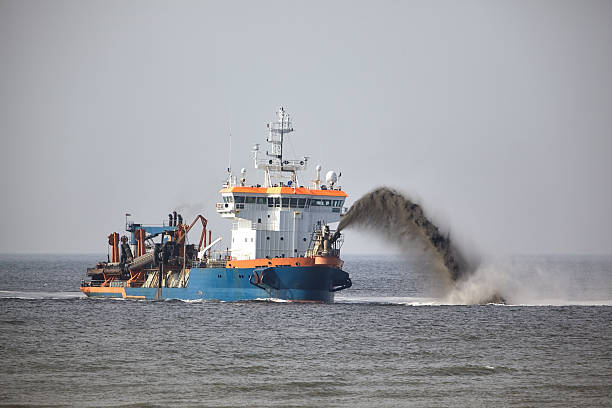 Ship spouting sand in front of the coast to gain new land from the sea.